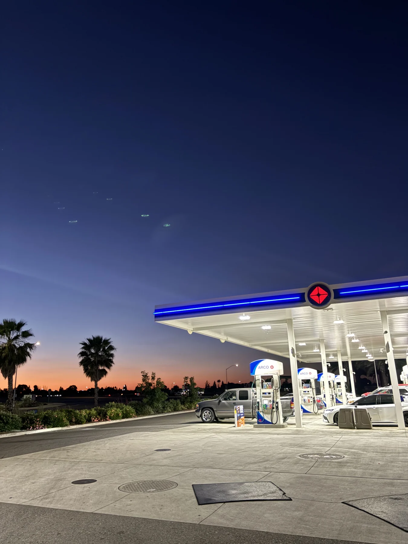 A gas station illuminated at dusk during a late-night drive